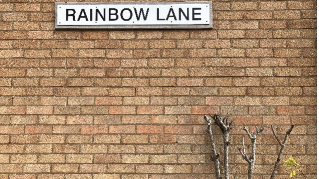A picture of the sign outside Rainbow lane on a brick wall