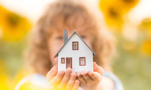 Hands holding a small toy house 