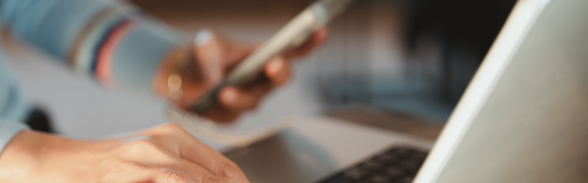 Someone in front of a laptop holding their smart phone