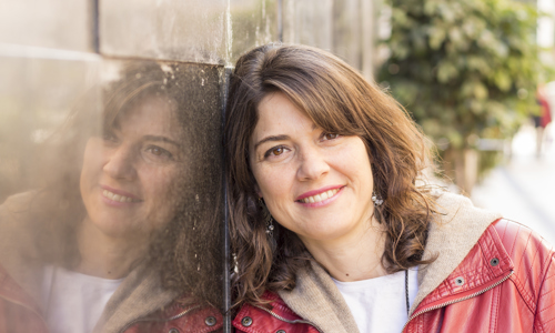 Woman smiling while leaning on wall