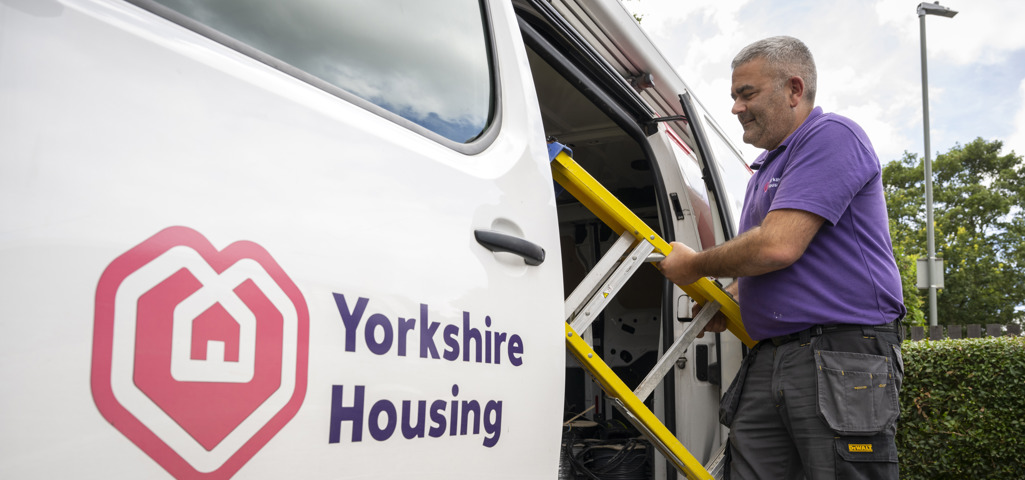 A Yorkshire Housing van with an open side door with a Yorkshire Housing colleague pulling a step ladder out of the van ready to do a repair! 