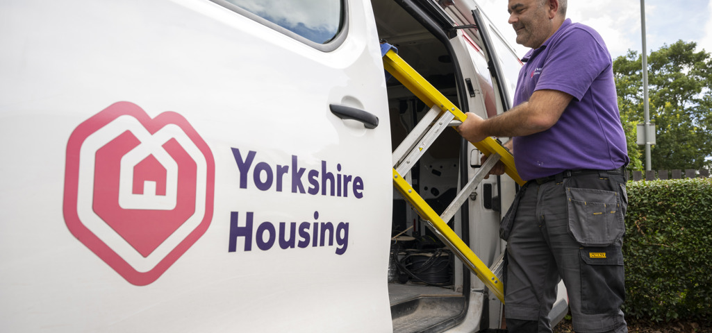 A Yorkshire eHousing van with an open side door with a Yorkshire Housing colleague pulling a step ladder out of the van ready to do a repair! 