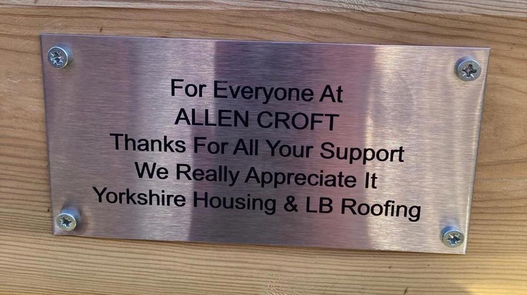 Close-up of a metal plaque on a bench given to customers reading “For everyone at Allen Croft, thanks for all your support”