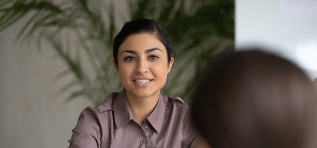 Woman sitting across desk from customer with sheet of paper giving advice 