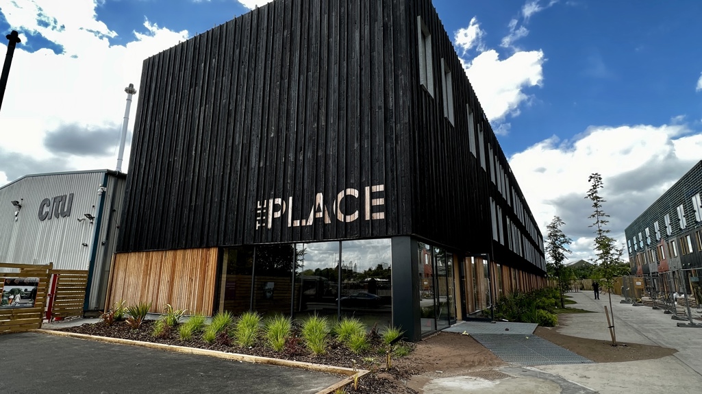 Picture of the outside of The Place, a black building with 'The Place' painted