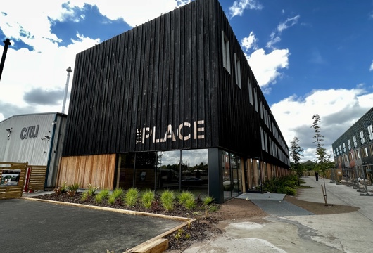 Picture of the outside of The Place, a black building with 'The Place' painted