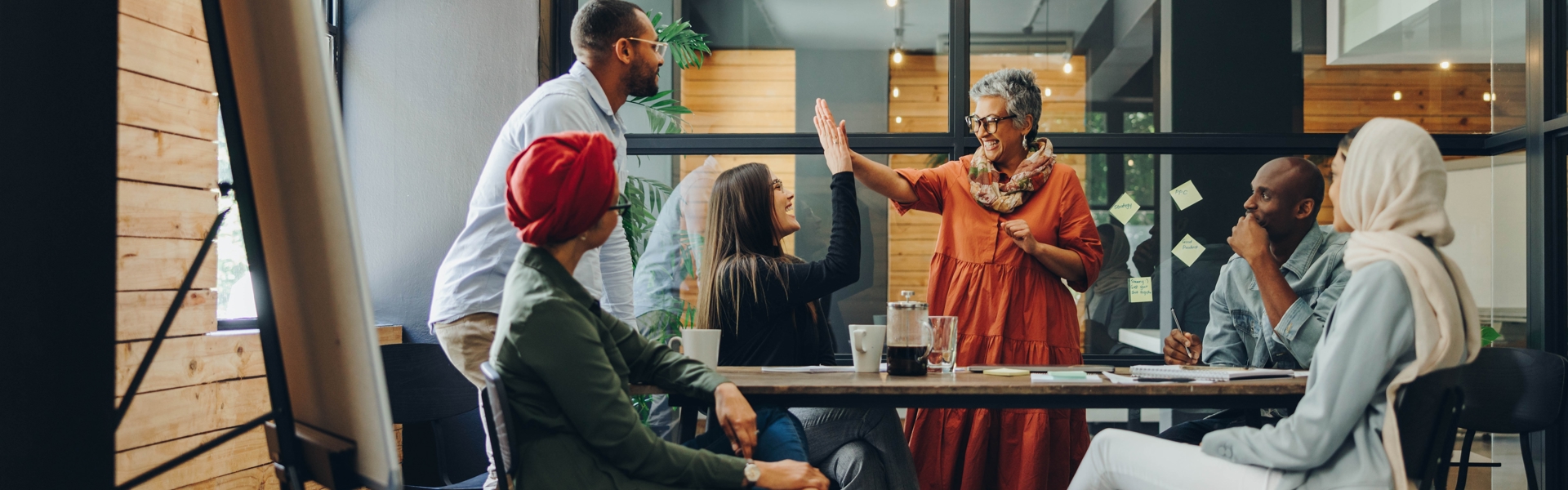 A group of office colleagues celebrating with two women high fiving in the middle