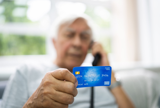 Elderly man on the telephone and holding a credit card in his hand