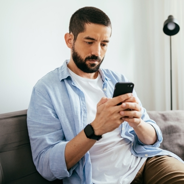 Man sat on the sofa looking at phone screen