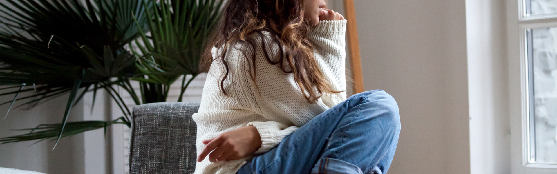 Young woman perched on a chair looking thoughtfully out of the window