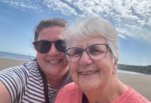 Two women taking selfie on beach smiling at camera