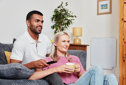 Couple sitting on sofa next to wall mounted heating panel