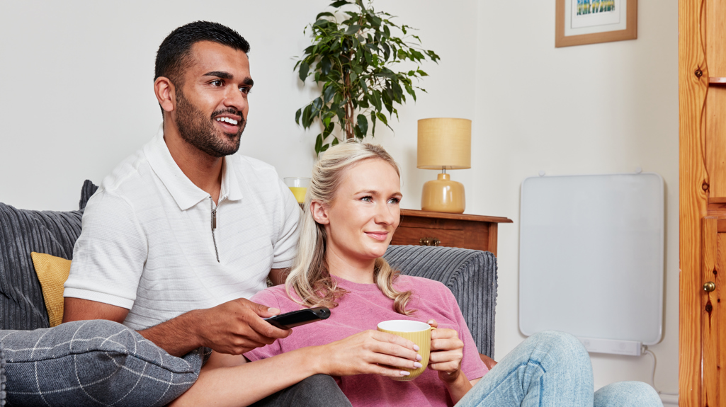 Couple sitting on sofa next to wall mounted heating panel