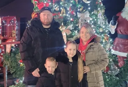 A young family stood in front of Christmas decorations