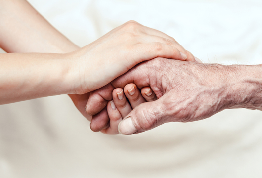 Photograph of two hands holding each other on a white background