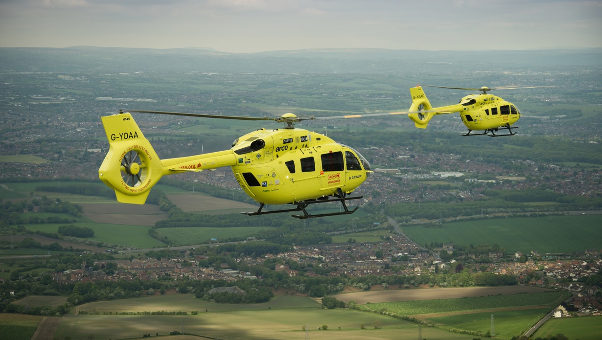 Two yellow Yorkshire Air Ambulances flying over countryside