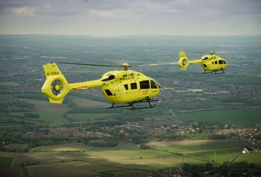 Two yellow Yorkshire Air Ambulances flying over countryside
