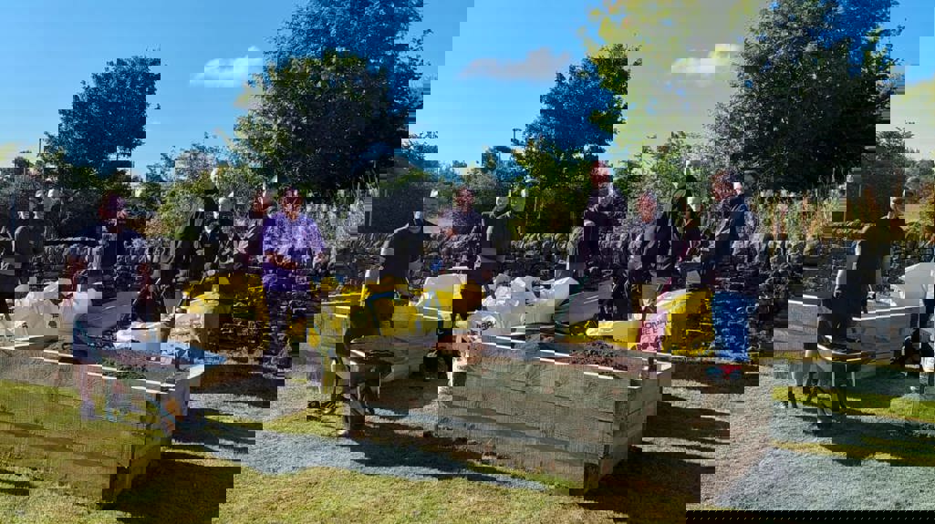 A photograph of Yorkshire Housing colleagues stood holding wheelbarrows and tools next to garden planters from the Big Day Out. 