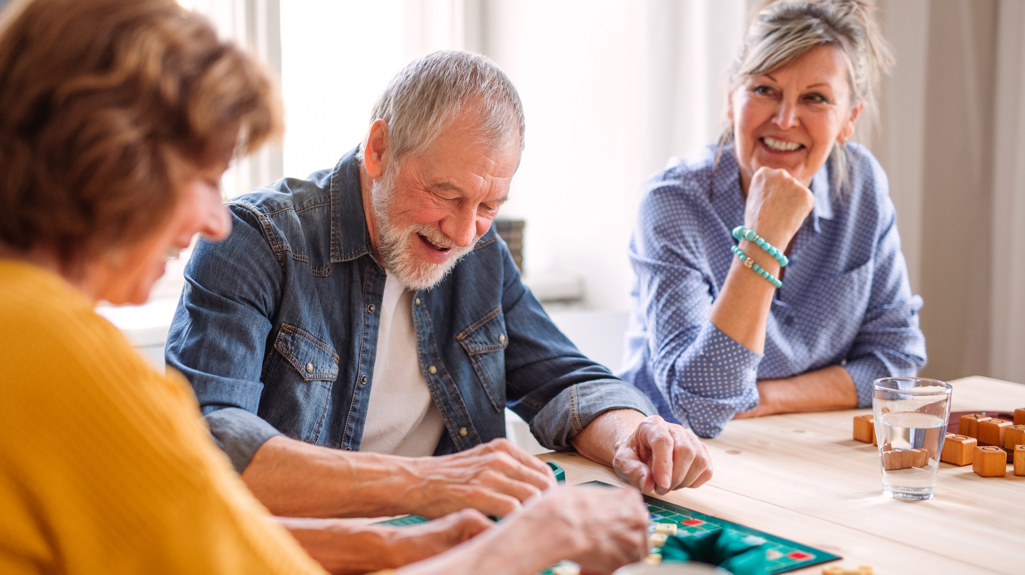 Two women and a man sitting at a table playing a board game