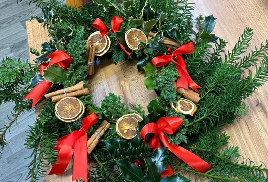 A wreath made by a customer at Rainbow Lane with red bows and dried orange slices on