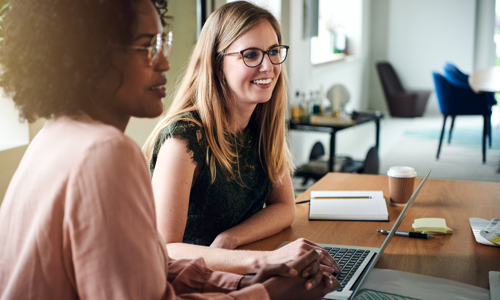 Two females smiling whilst working together