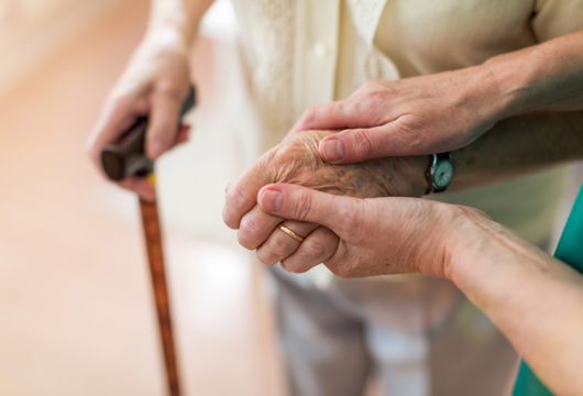 Picture of someone holding a pensioners hand whilst they walk together