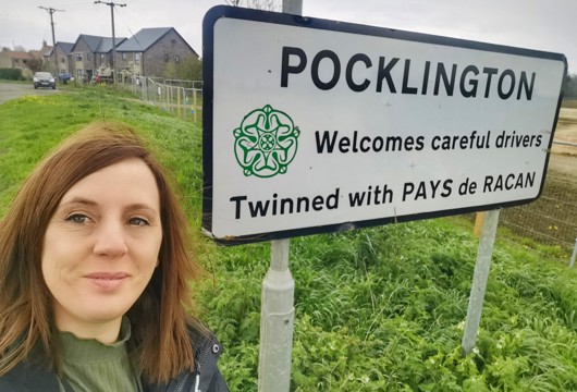 Leanne taking a selfie by the Pocklington town sign saying it pairs with Pays de Racan 