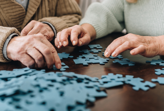 Two people sitting at table sorting out jigsaw puzzle pieces