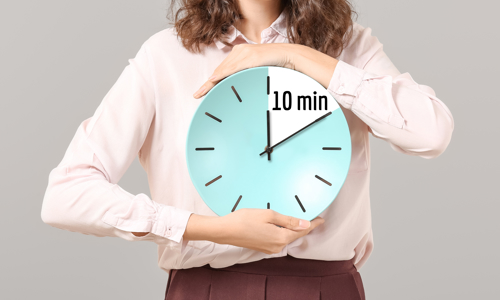 A woman in a pink shirt holding a clock that shows 10 minutes countdown 