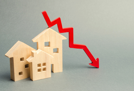 Small wooden toy houses with a red downward arrow above.