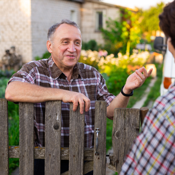 Picture of an older man speaking to someone over a garden fence