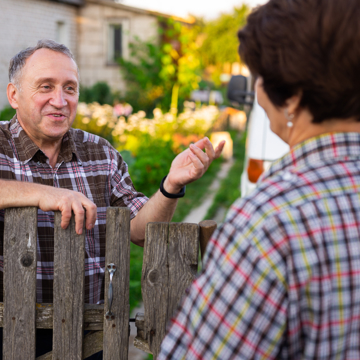 Picture of an older man speaking to someone over a garden fence