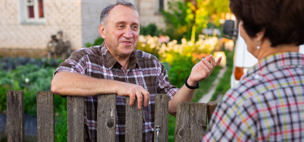 Picture of an older man speaking to someone over a garden fence