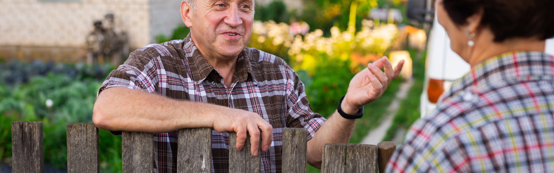 Picture of an older man speaking to someone over a garden fence
