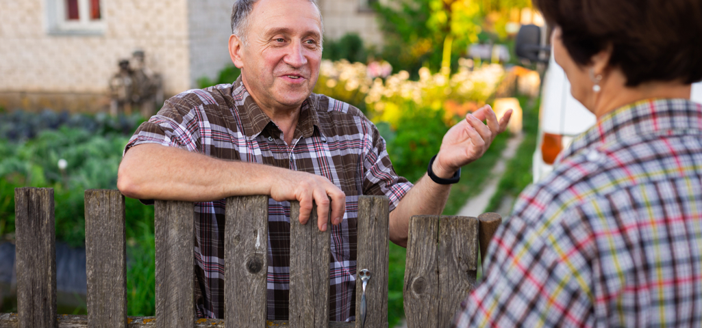 Picture of an older man speaking to someone over a garden fence