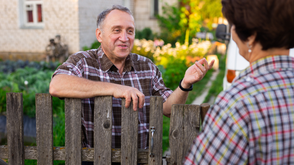 Picture of an older man speaking to someone over a garden fence