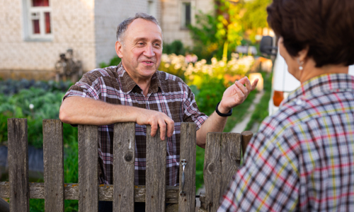 Picture of an older man speaking to someone over a garden fence