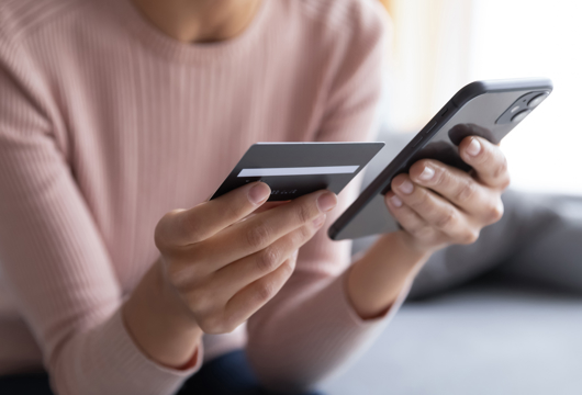 Female holding mobile phone and debit card