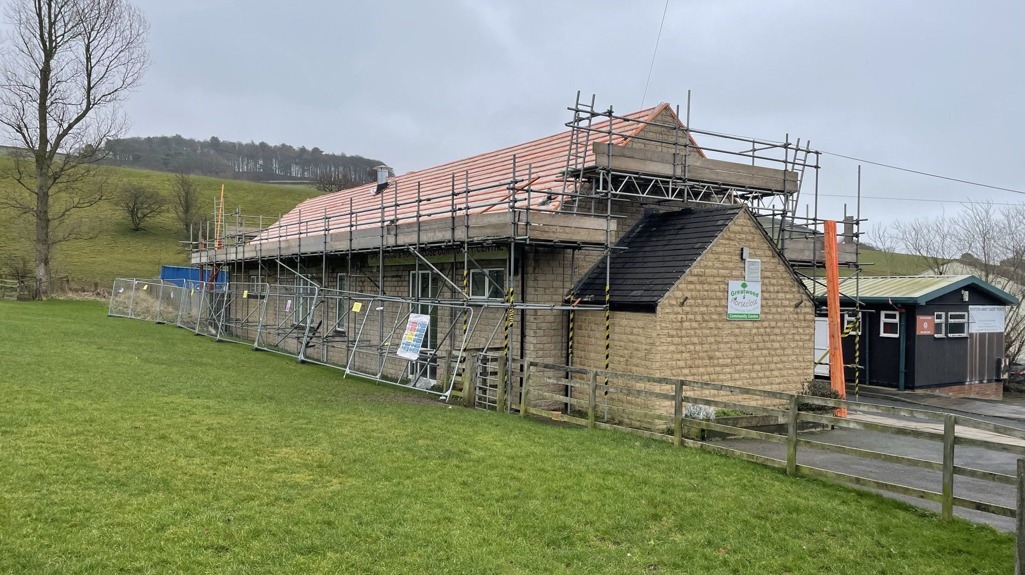 A close up picture of a community centre with scaffolding in place as it gets its new roof. 