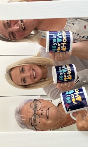 Three ladies holding up mugs together which say Your Voice, Your Home