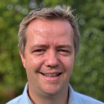 Man in blue shirt smiling at the camera 