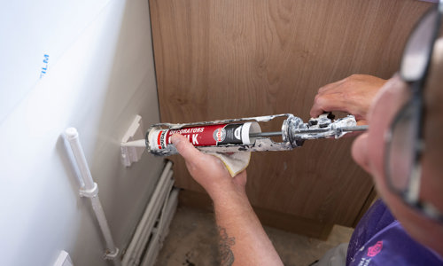 Man with glasses putting polyfiller on the wall, doing some DIY 