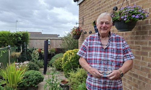 Our customer John stood holding his trophy in his garden