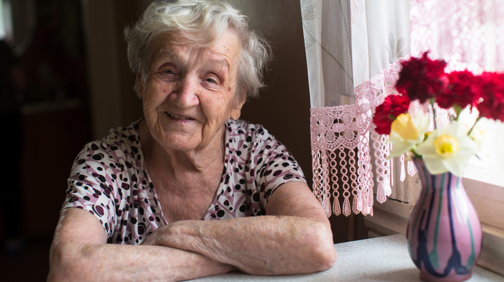 Older woman sitting at window smiling at camera