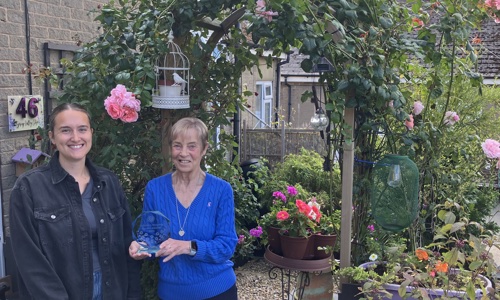 Our customer Susan holding her trophy under her rose arch in her garden